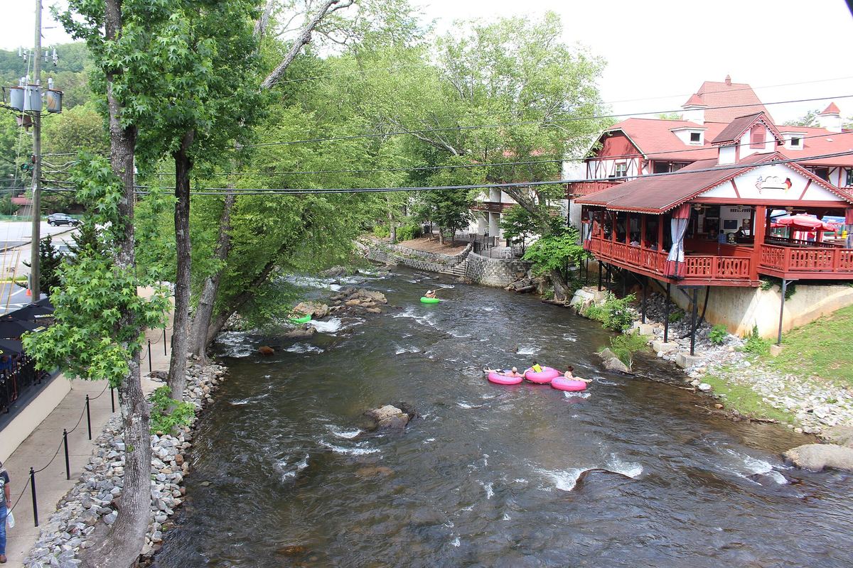 Tubers floating down the shallow, rocky Chattahoochee River past Bavarian-style buildings in Helen